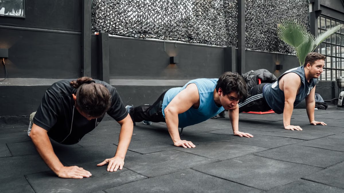Men performing push-ups during a group workout session in Mexico City gym.